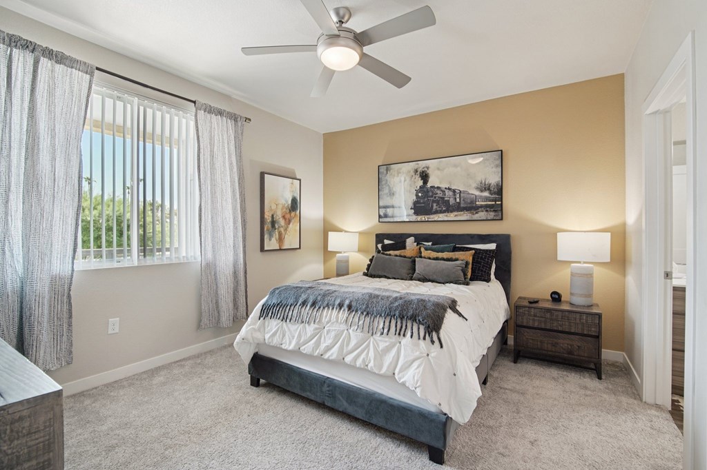 A bedroom with a large bed and a ceiling fan.