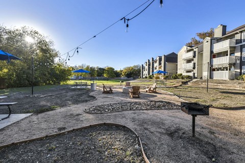 A playground with a swing set and a slide in the foreground and apartment buildings in the background.