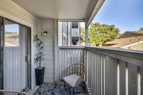A balcony with a chair and a potted plant.