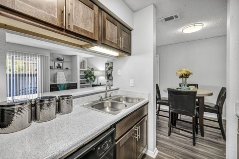 A kitchen with a sink, stove, and a dining table with chairs.