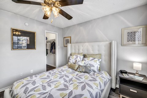 A bedroom with a bed, a ceiling fan, and a nightstand.