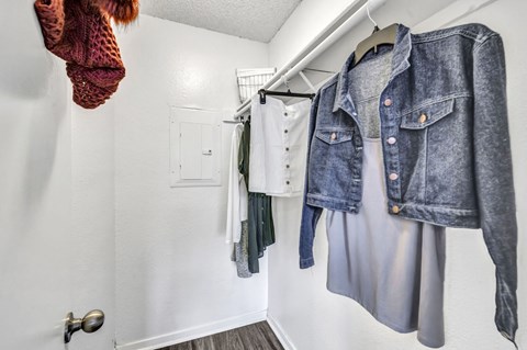 A denim jacket is hanging on a white wall next to a white door.