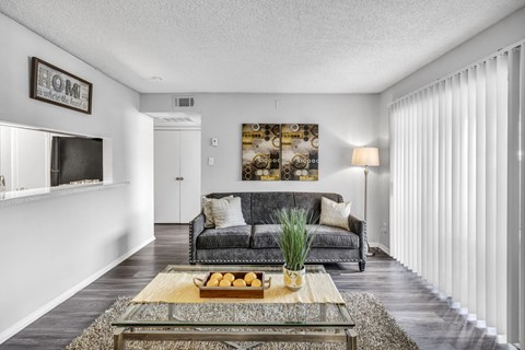 A living room with a grey couch and a coffee table with a tray of fruit on it.