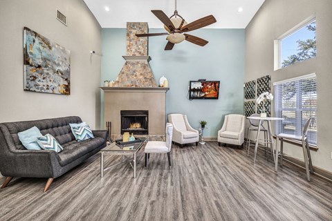 A living room with a grey couch, a fireplace, and a ceiling fan.