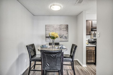 A dining room with a table set for two and a painting on the wall.