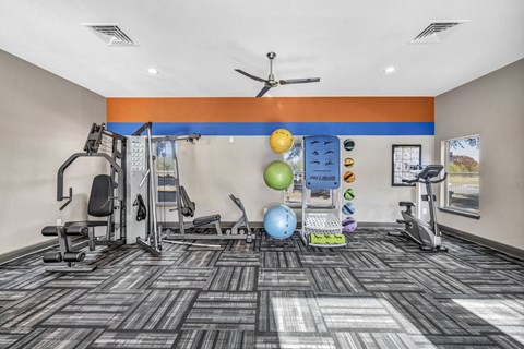 A gym with a variety of equipment including a treadmill, weights, and a fan.