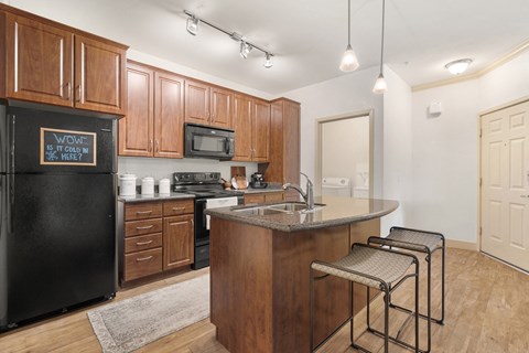 a kitchen with wooden cabinets and a counter top and a black refrigerator