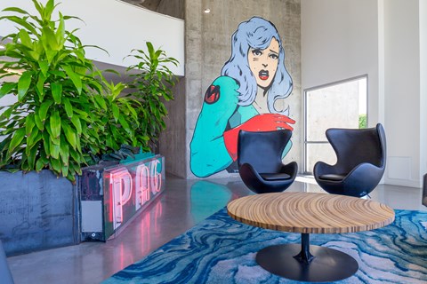 A woman with blue hair and a red dress is standing in a room with a sign that says "PAG".