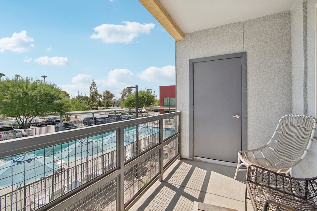 A balcony with a chair and a pool in the background.