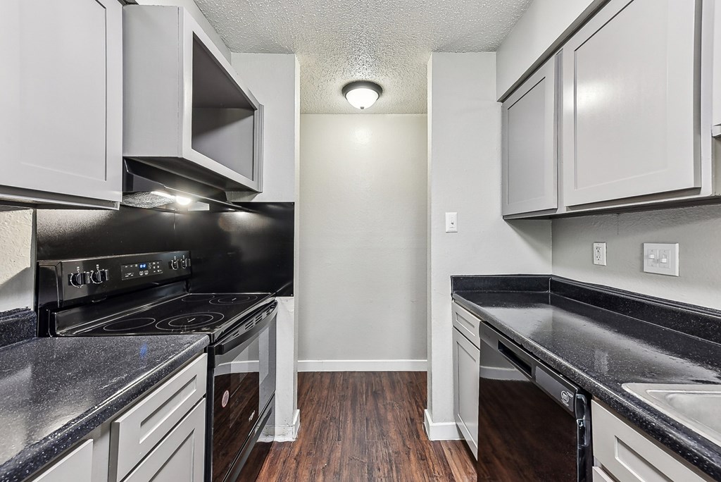 A kitchen with black countertops and white cabinets.