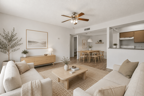 A living room with a beige couch, a coffee table, and a ceiling fan.
