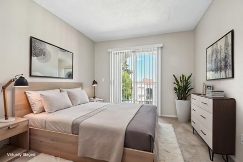 A bedroom with a large bed, a nightstand, and a dresser.