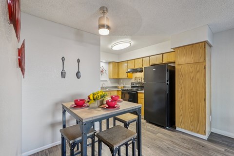 A kitchen with a table and chairs in the foreground and a refrigerator in the background.