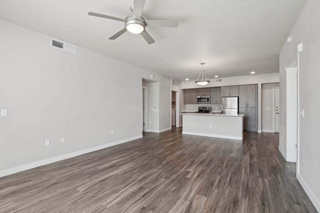 A room with a ceiling fan and wooden flooring.