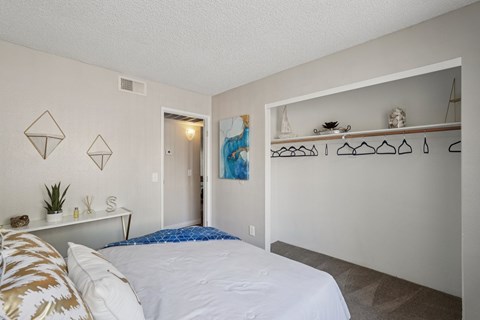 A bedroom with a bed, pillows, and a painting on the wall.