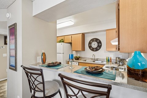 A kitchen with a table and two chairs.