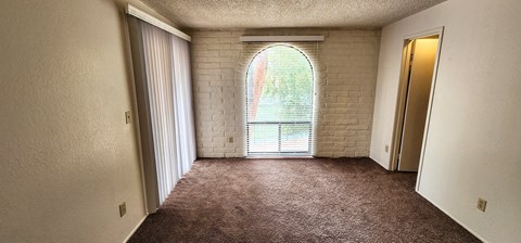 a living room with an arched window and carpet