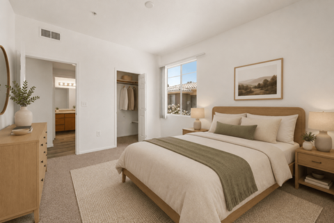 A bedroom with a large bed and a view of a house through the window.
