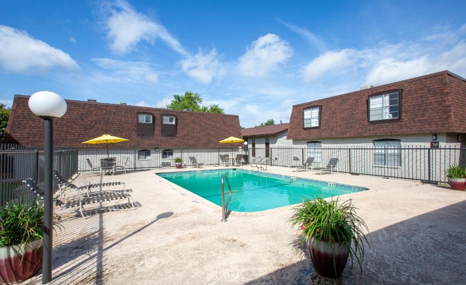 A pool area with a blue pool and yellow umbrellas.