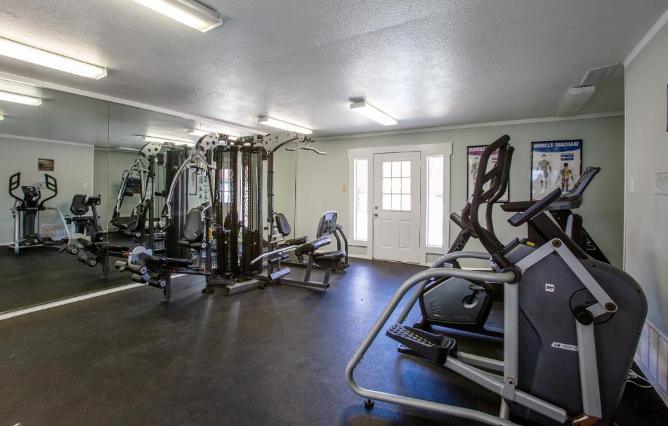A spacious gym with a variety of equipment including treadmills, elliptical machines, and weight machines.
