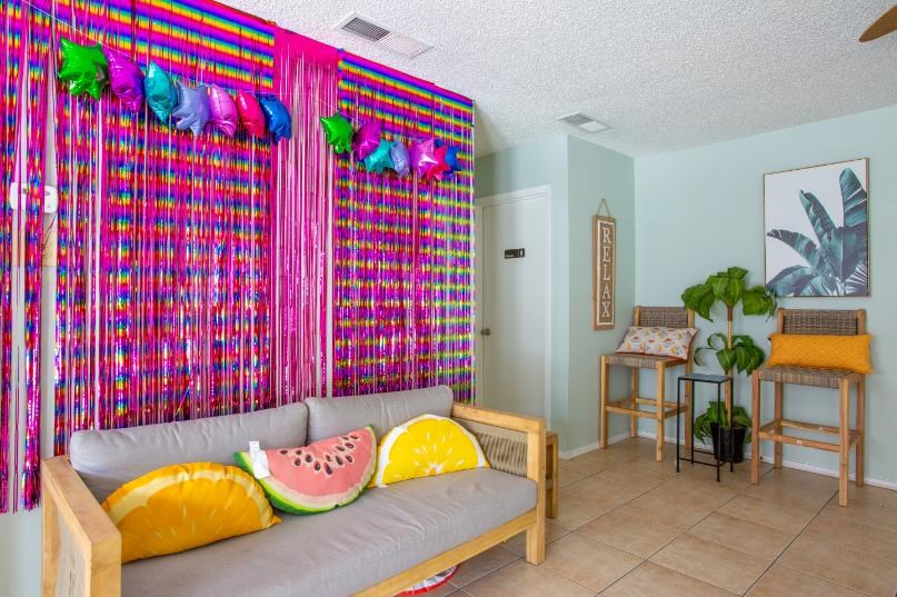 A room with a couch and a wall hanging with fruit pillows.
