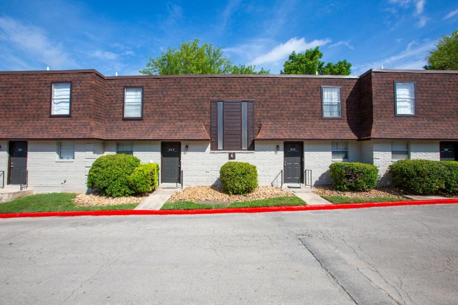 A building with a red roof and a parking lot in front.