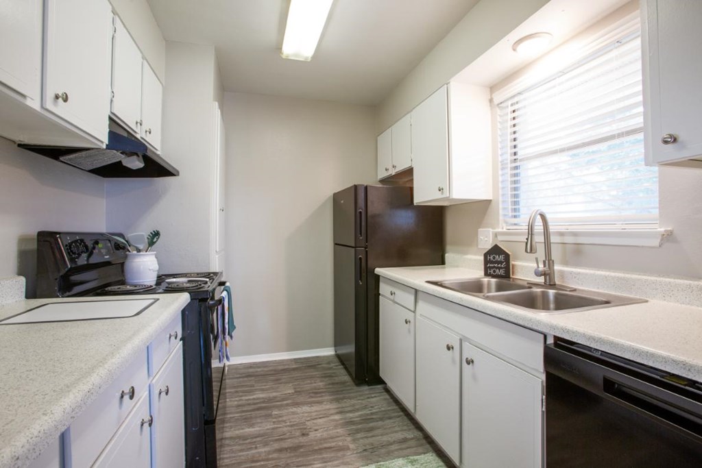 A kitchen with white cabinets and a black refrigerator.