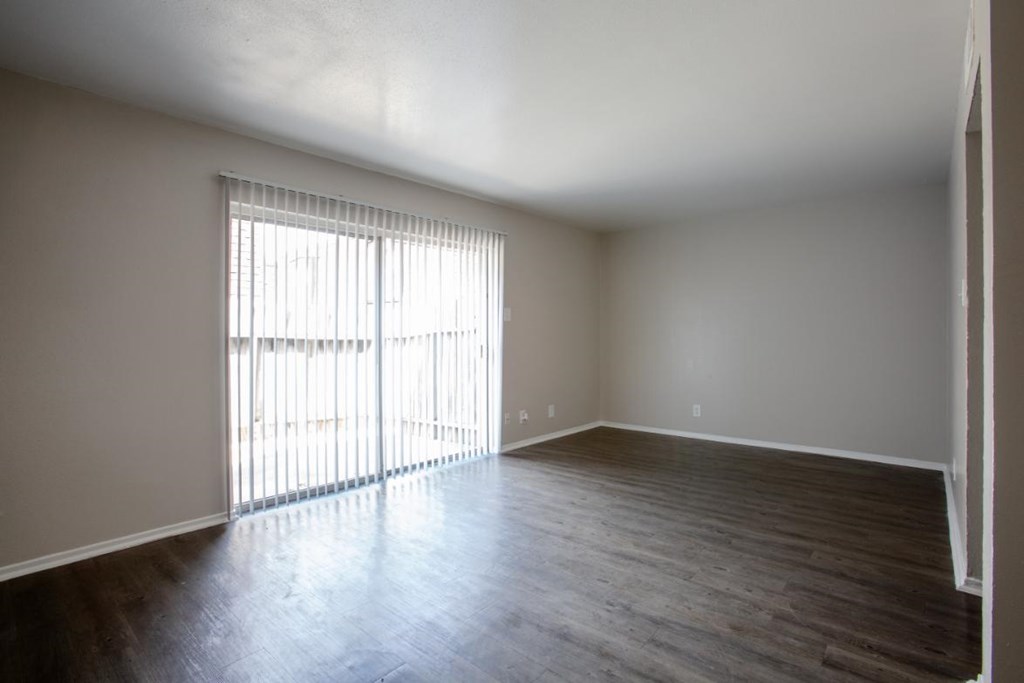 A room with wooden floors and a window with blinds.