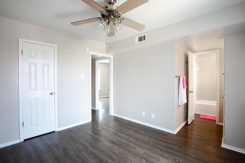 A room with a ceiling fan and wooden floors.