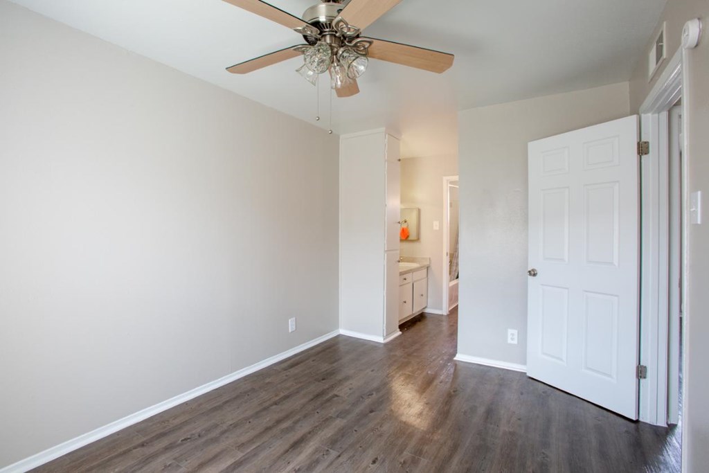 A room with a ceiling fan and wooden floors.