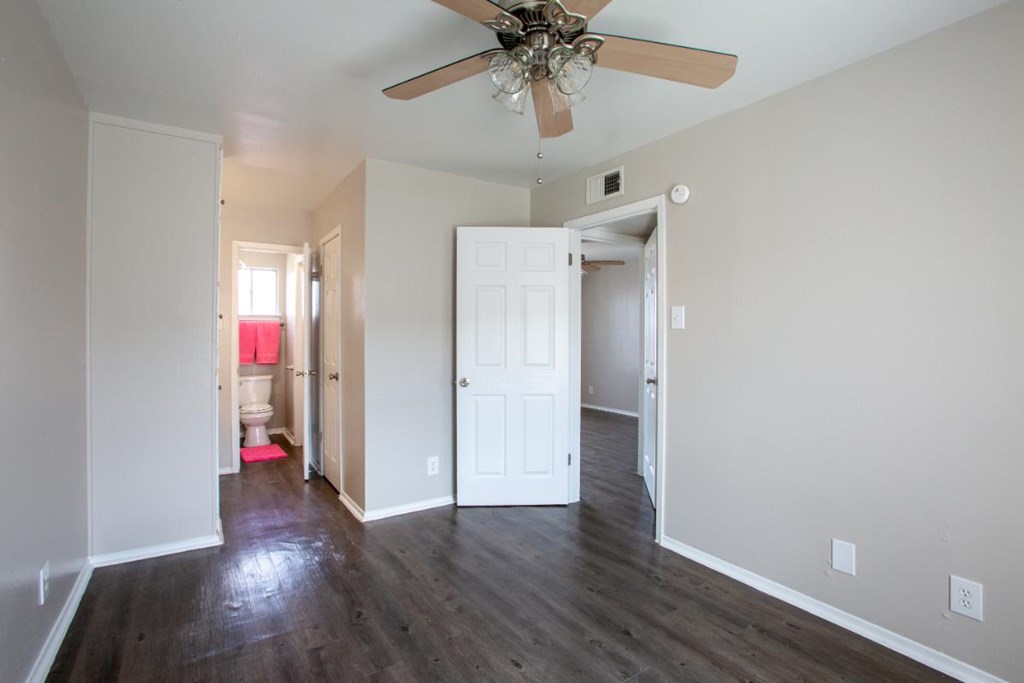 A room with a ceiling fan and wooden floors.