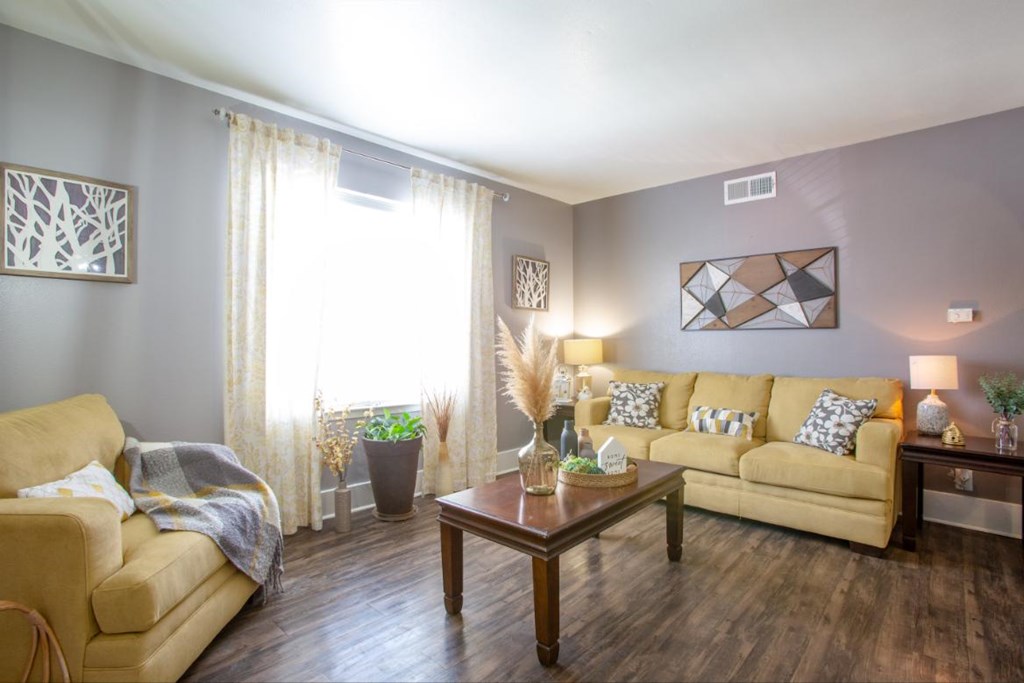 A living room with a tan couch, a coffee table, and a lamp.