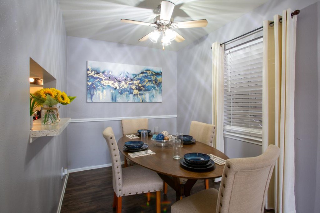 A dining room with a table set for two and a painting on the wall.