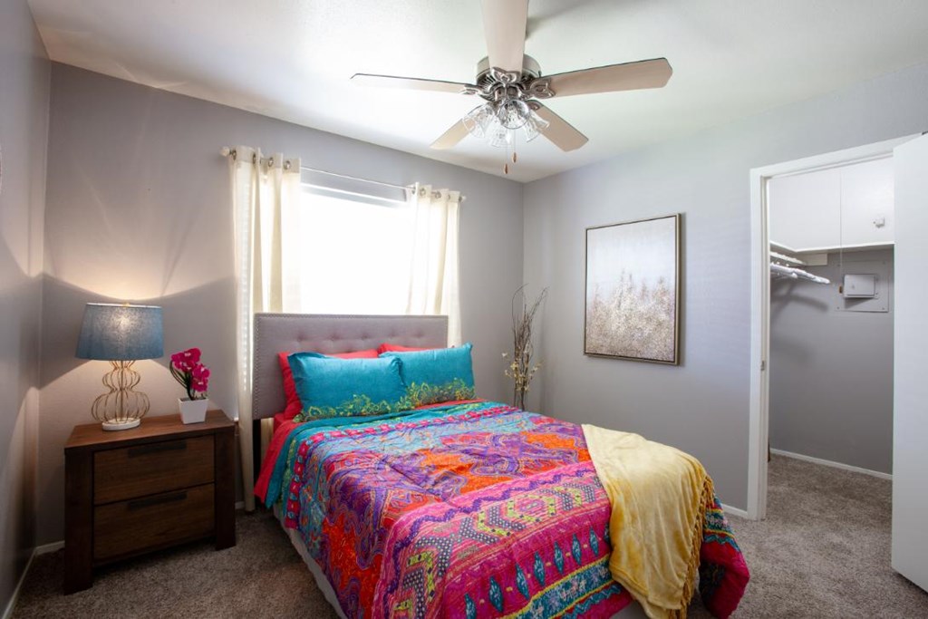 A bedroom with a bed, nightstand, and a ceiling fan.