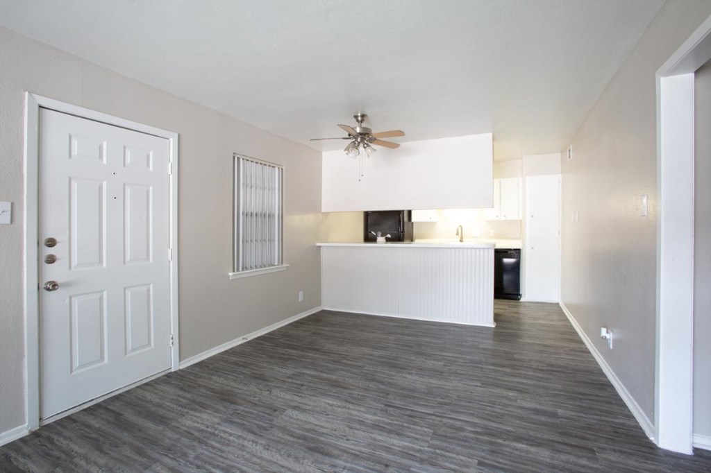 A room with a white door, a ceiling fan, and a window with blinds.