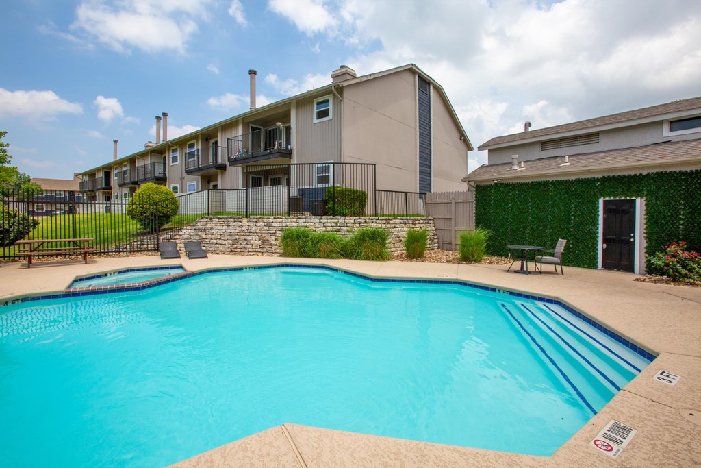 A swimming pool in a residential area with a green wall on the right.