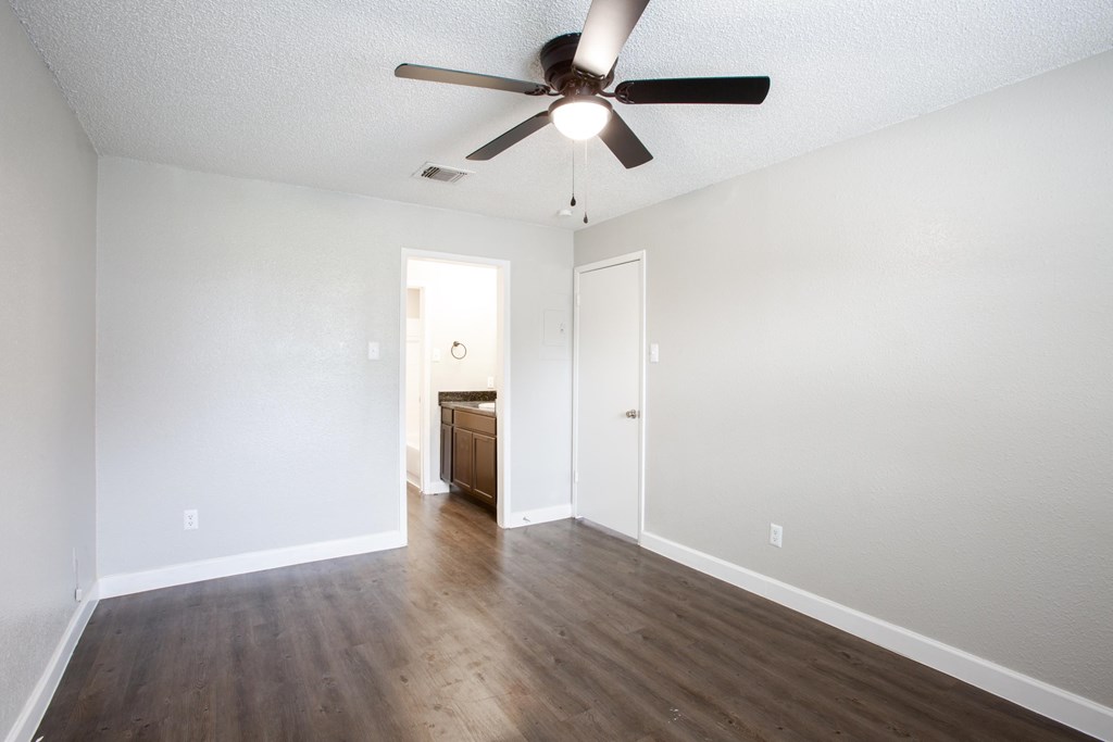 A room with a ceiling fan and wooden floors.