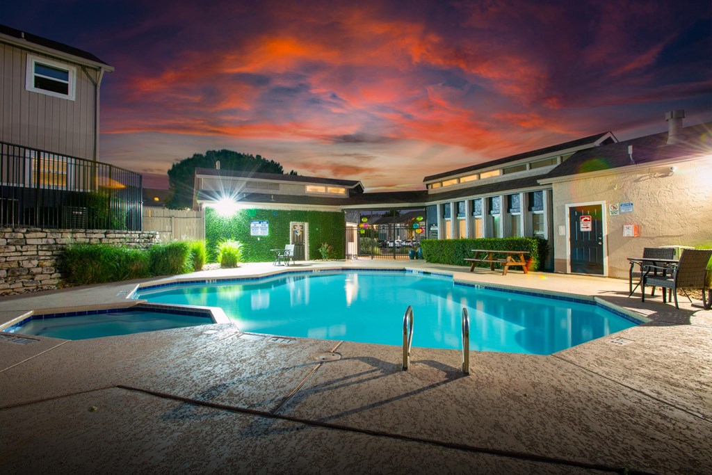 A swimming pool at night with lights on.