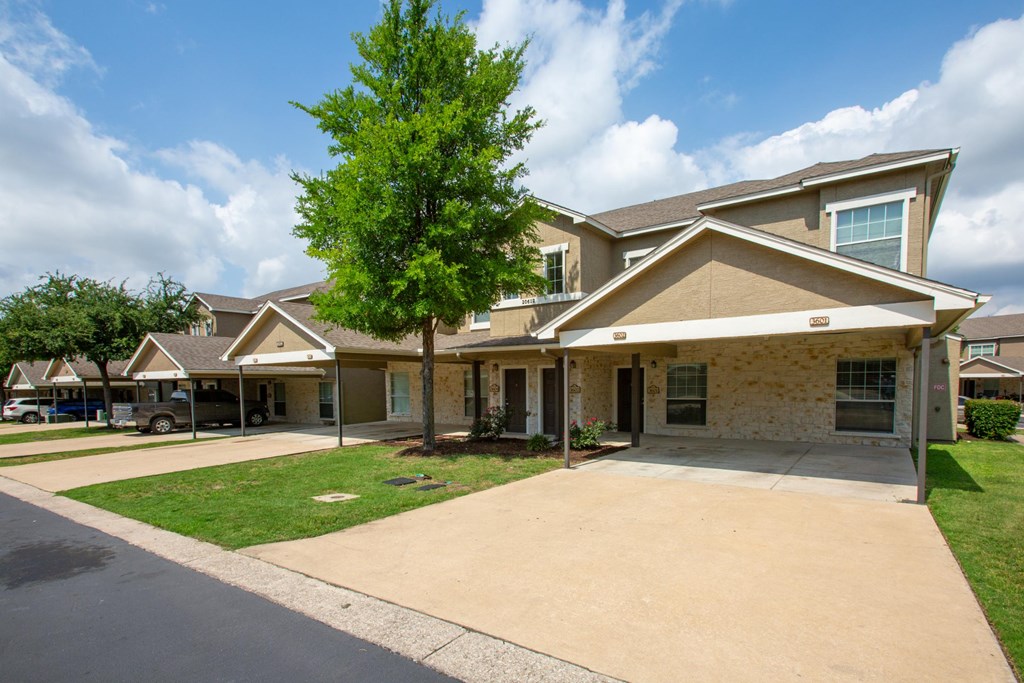 A row of houses with a tree in front of the first one.