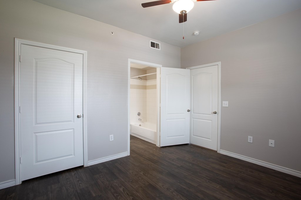 A room with a ceiling fan and three doors.