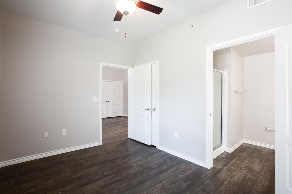 A room with a ceiling fan and wood flooring.