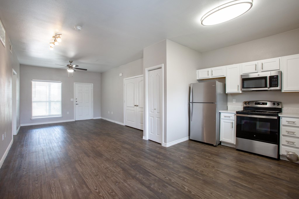 A kitchen with white cabinets and a wood floor.