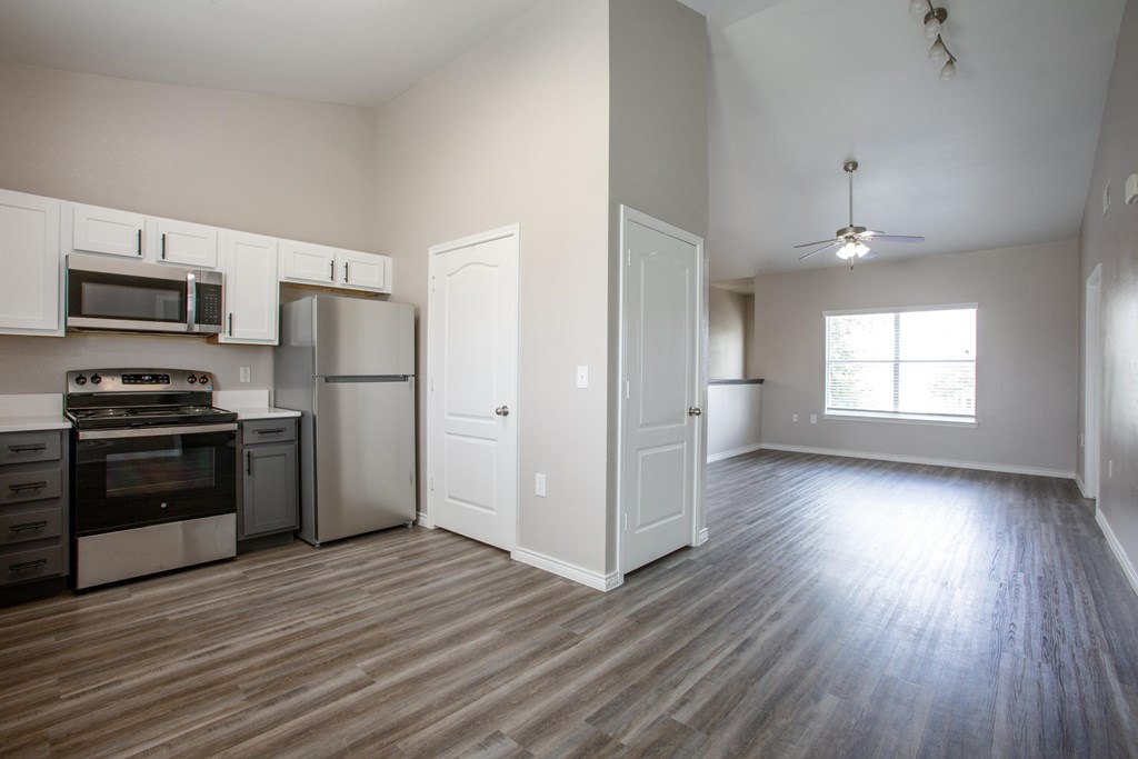 A kitchen with white cabinets and a wooden floor.