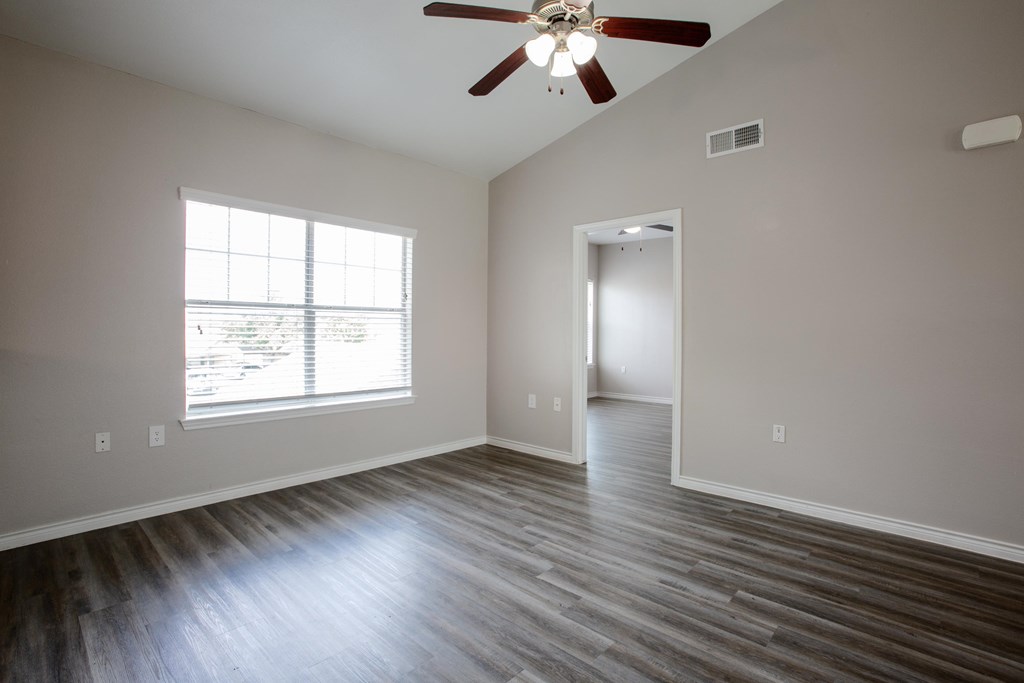 A room with a ceiling fan and a window with blinds.