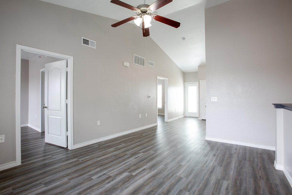 A room with a ceiling fan and wood flooring.