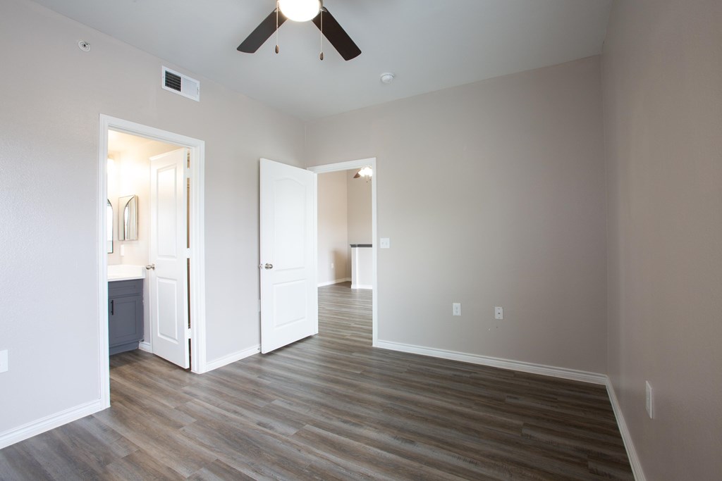 A room with a ceiling fan and wooden flooring.