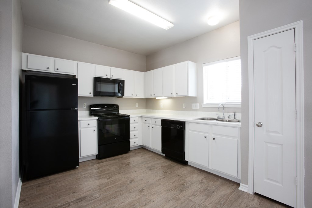 A kitchen with black appliances and white cabinets.