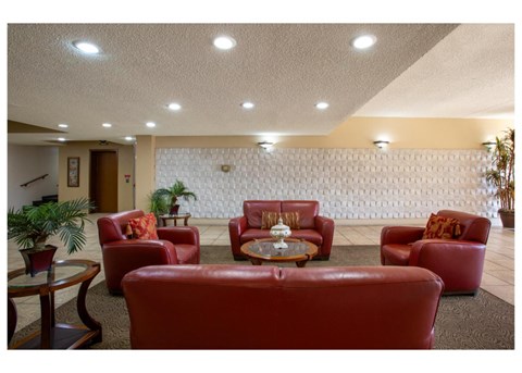 A living room with red couches and a white wallpaper.
