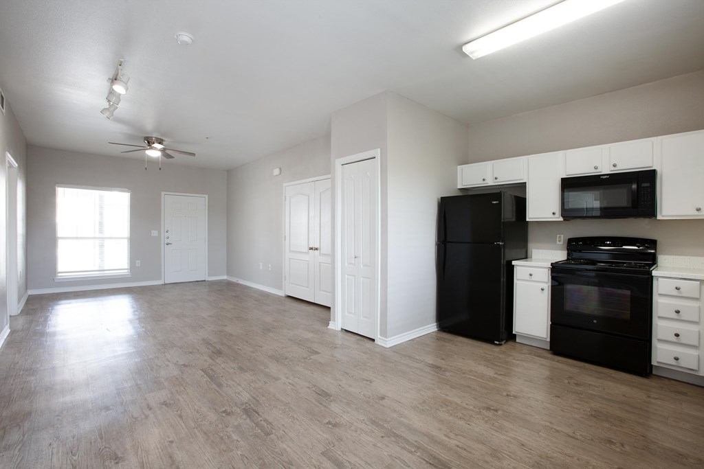 A spacious kitchen with black appliances and white cabinets.