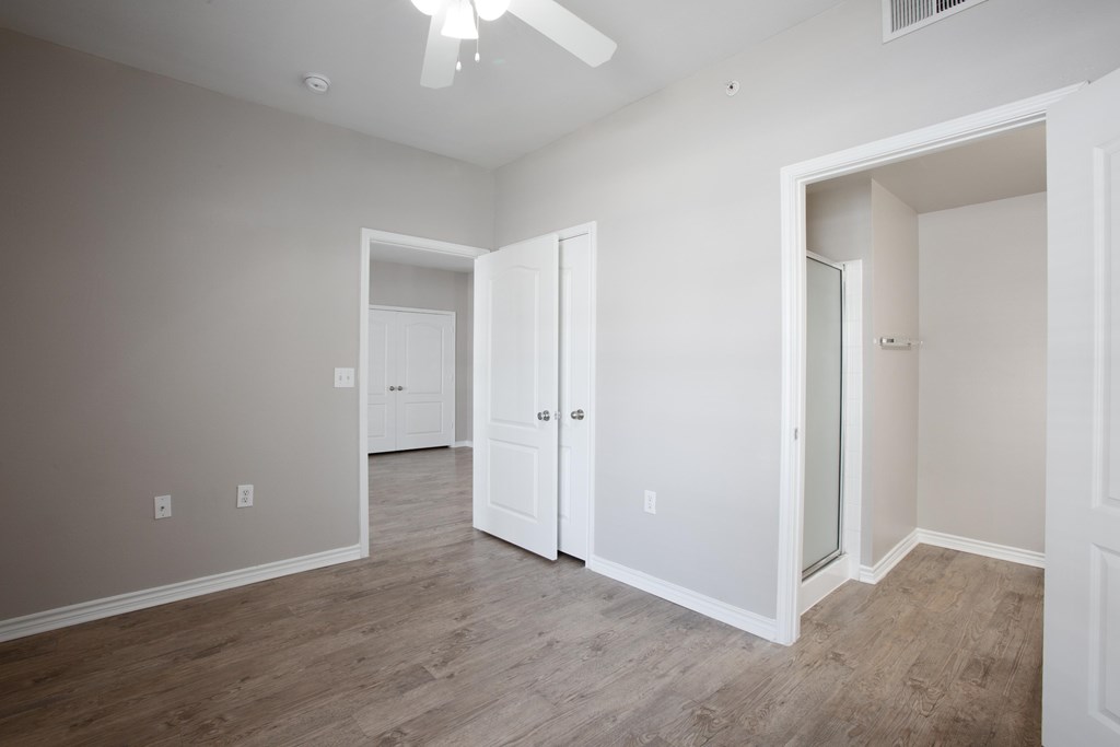 A room with a ceiling fan and three doors.